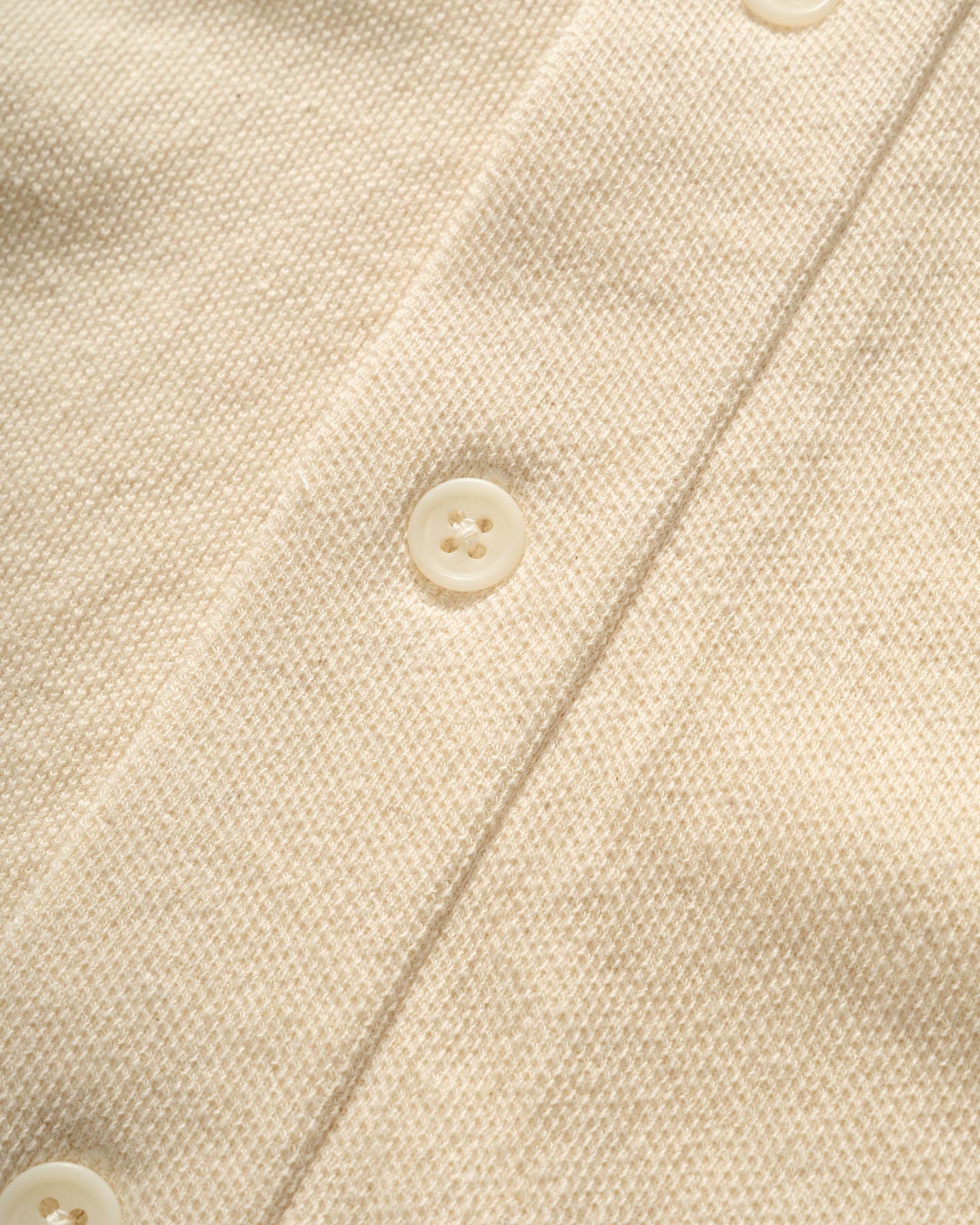 Close-up of a IKIJI Work Jacket beige fabric with a button and stitching detail