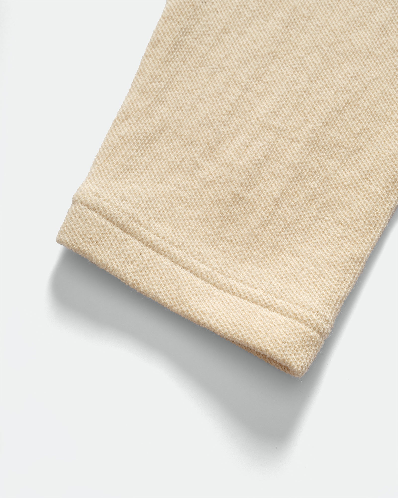 Close-up of IKIJI White Work Jacket cuffs and textured fabric on grey background.