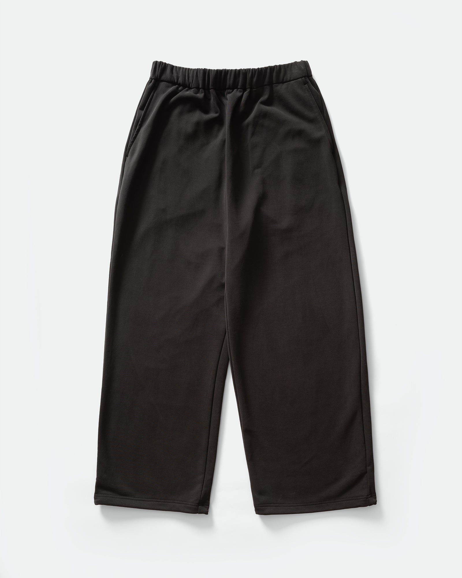 Pack shot of KANAMASA PHIL Black Cupro Easy Pants with elasticated waistband on a grey background.