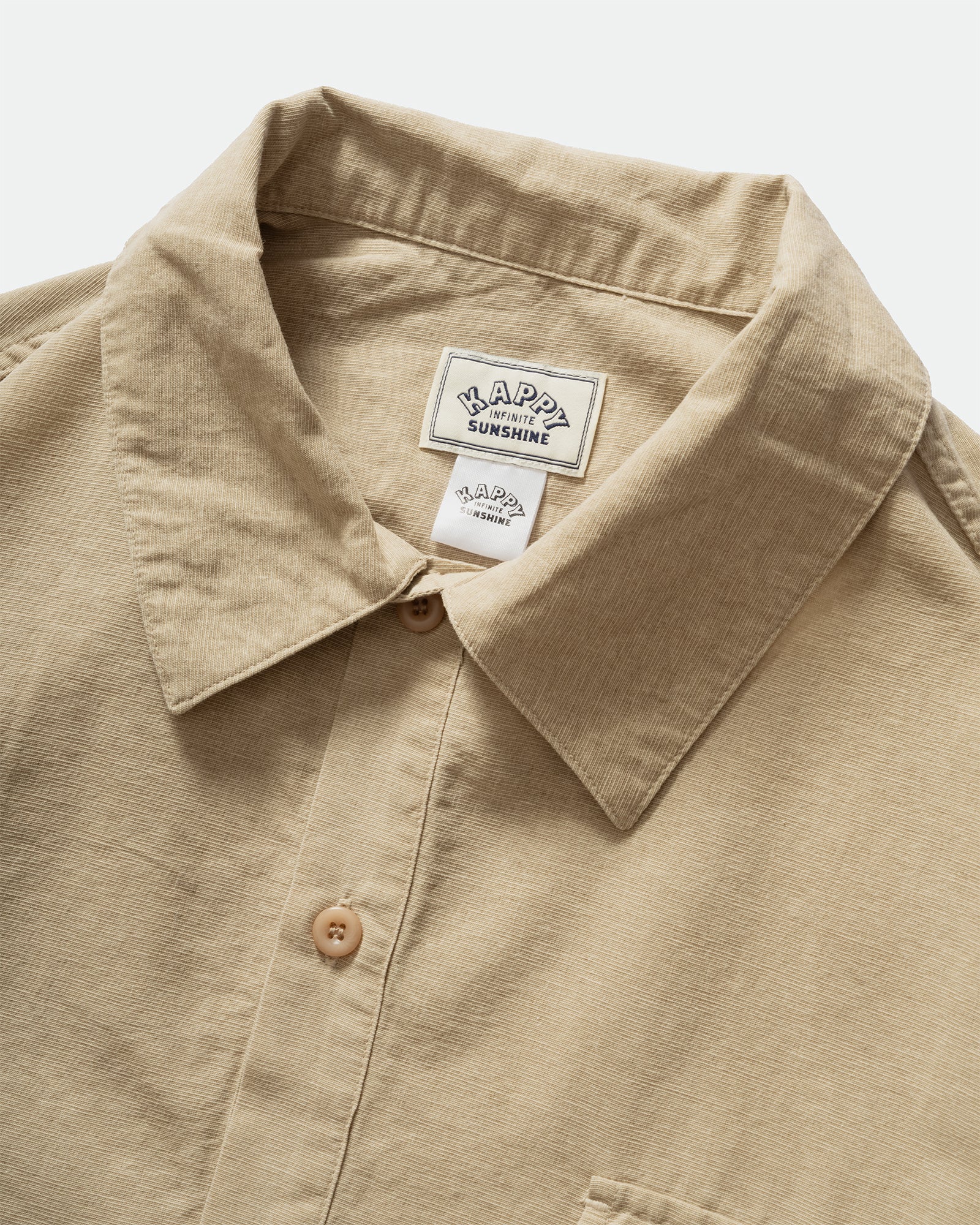 Close up of Kappy beige Pigment Henleyneck short sleeve Shirt with a collar, labelling, and two button lapel on a grey background 