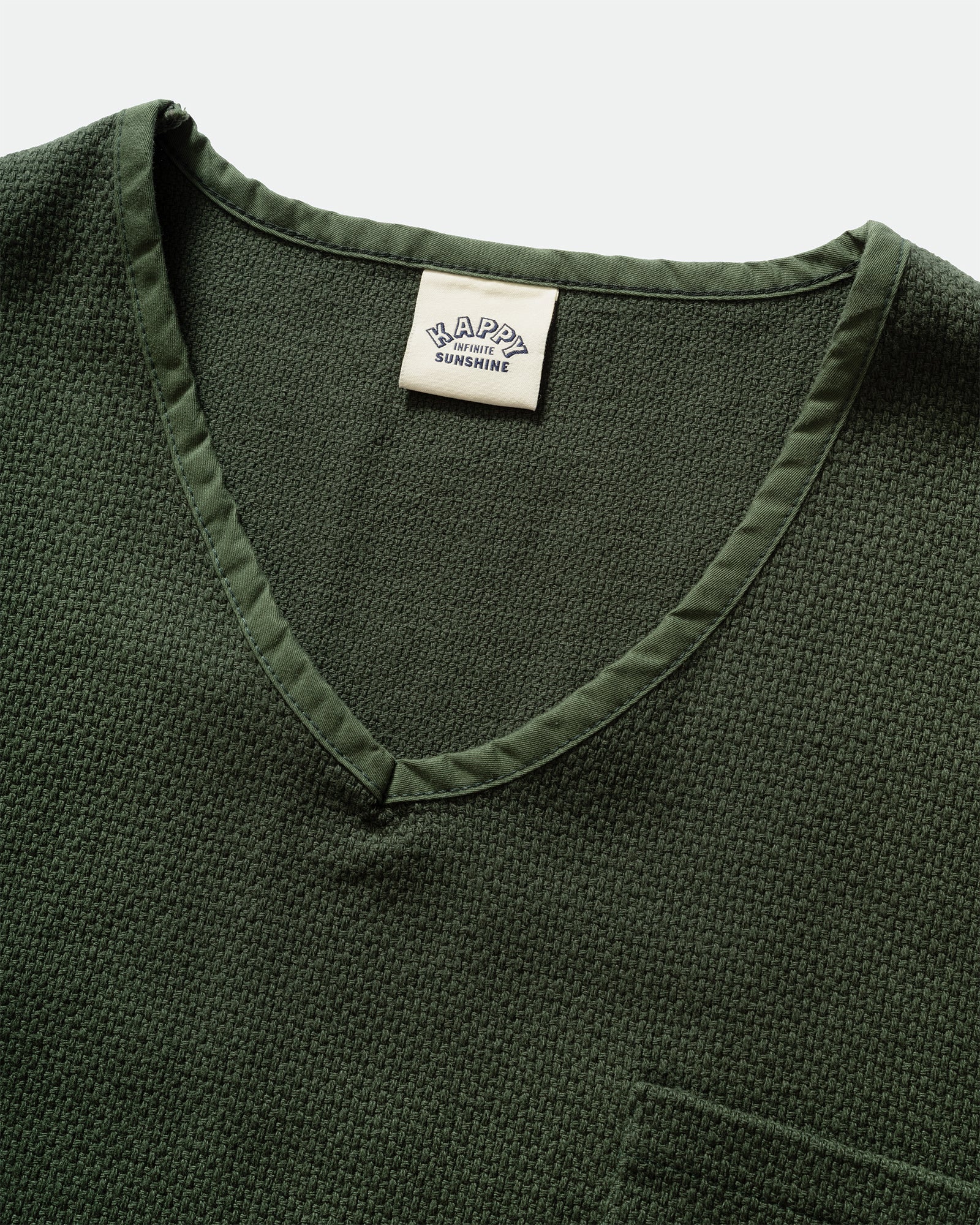 Close up of a Kappy Green Woven Sweater vest with branded label and v-neckline on a grey background  