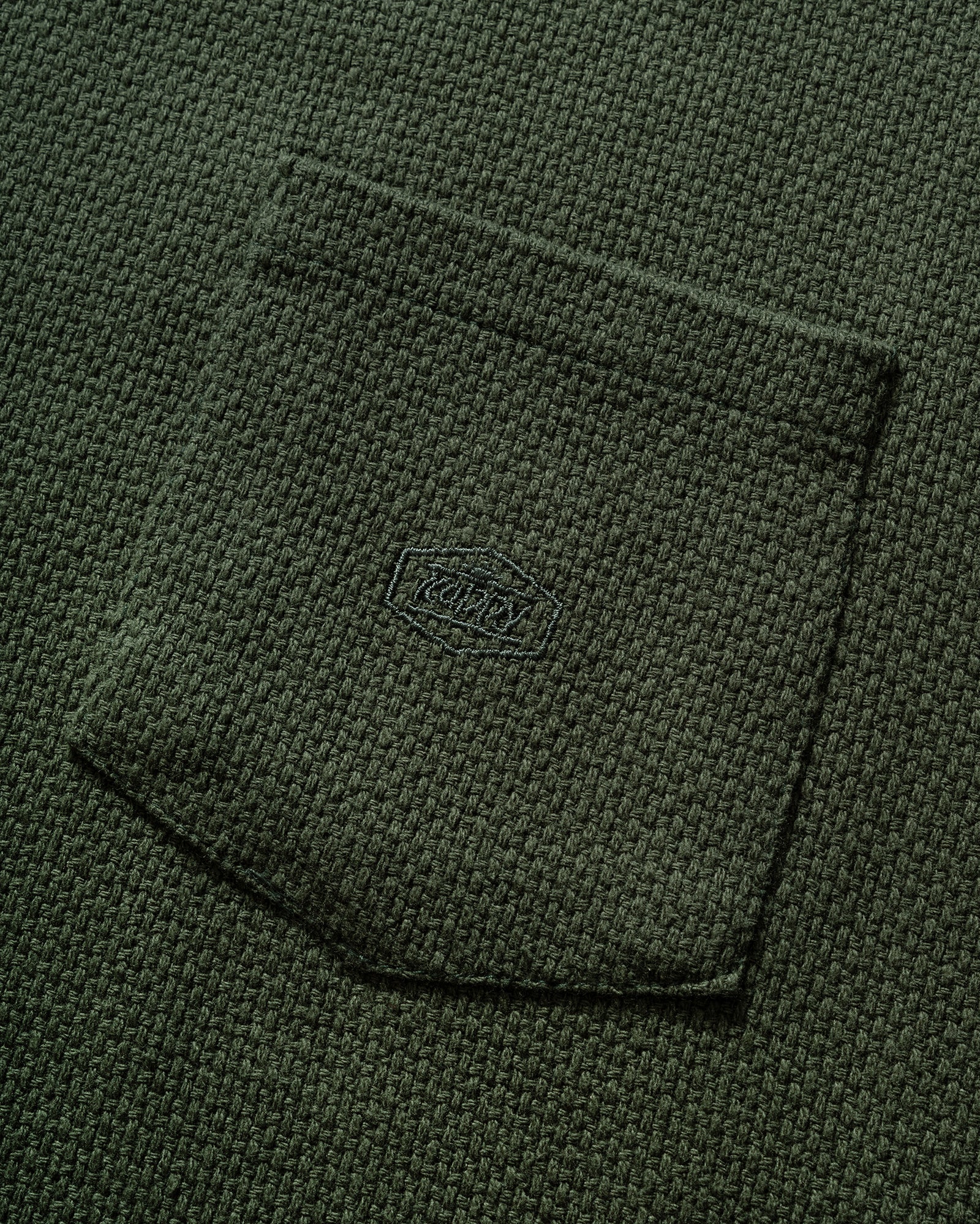 Close up of a Kappy Green Woven Sweater vest with check patch pocket and branded embroidery