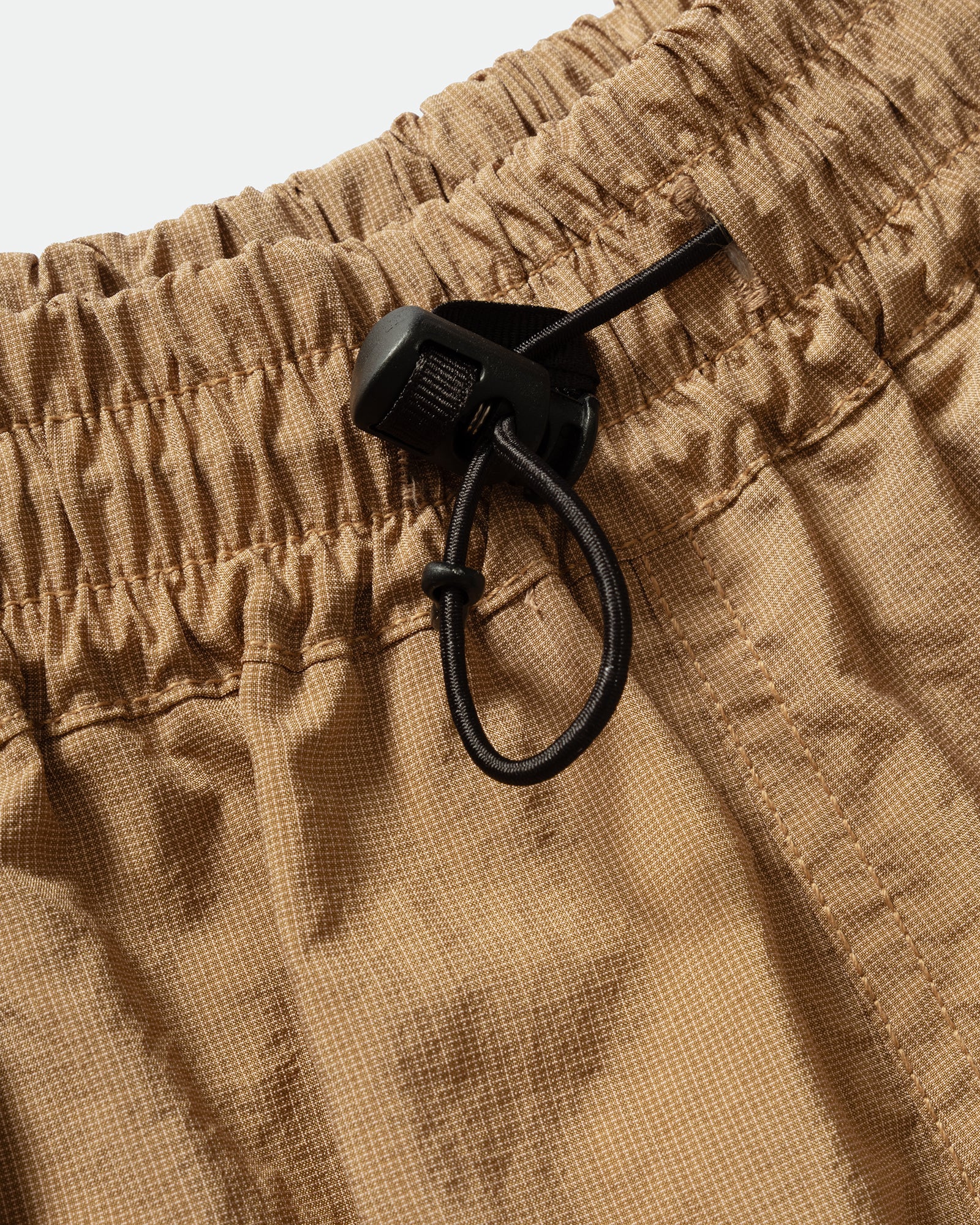 Close-up of brown kappy nylon shorts with a black drawstring and elasticated waistband.