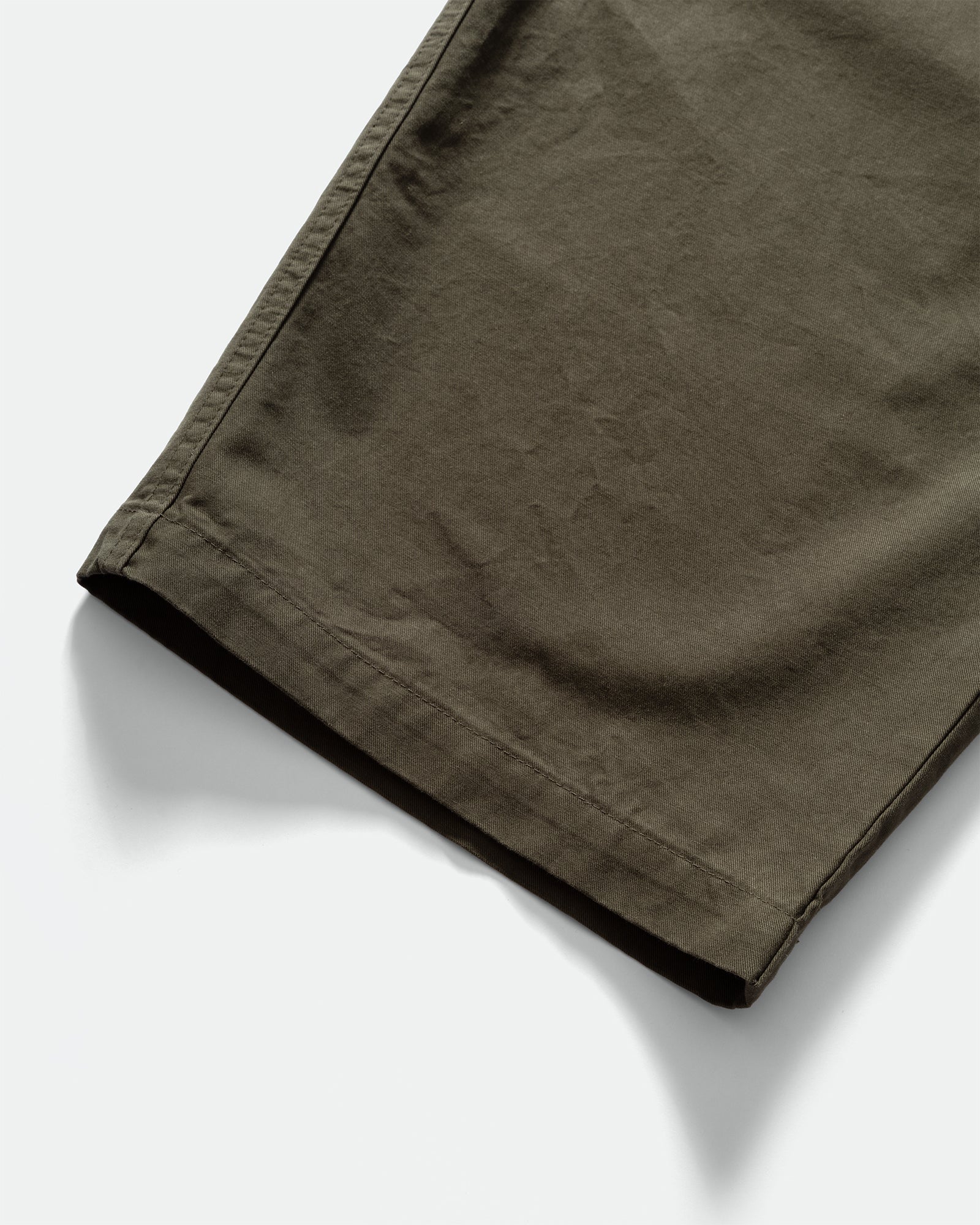 Close-up of dark green Kappy Pintuck Wide Chino Pants cuffs on a grey background