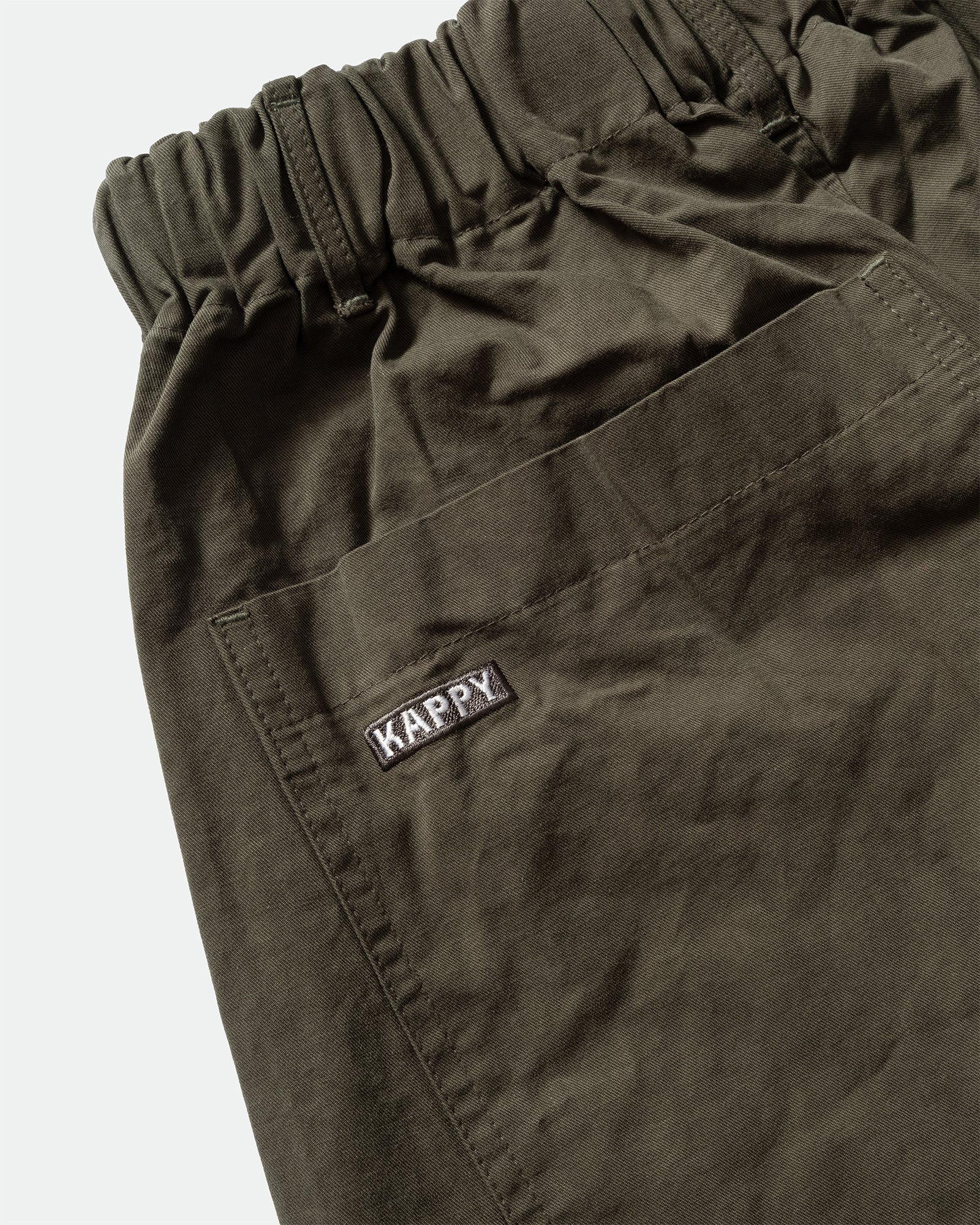 Close-up of dark green Kappy Pintuck Wide Chino Pants back patch pocket with branded patch embroidery 