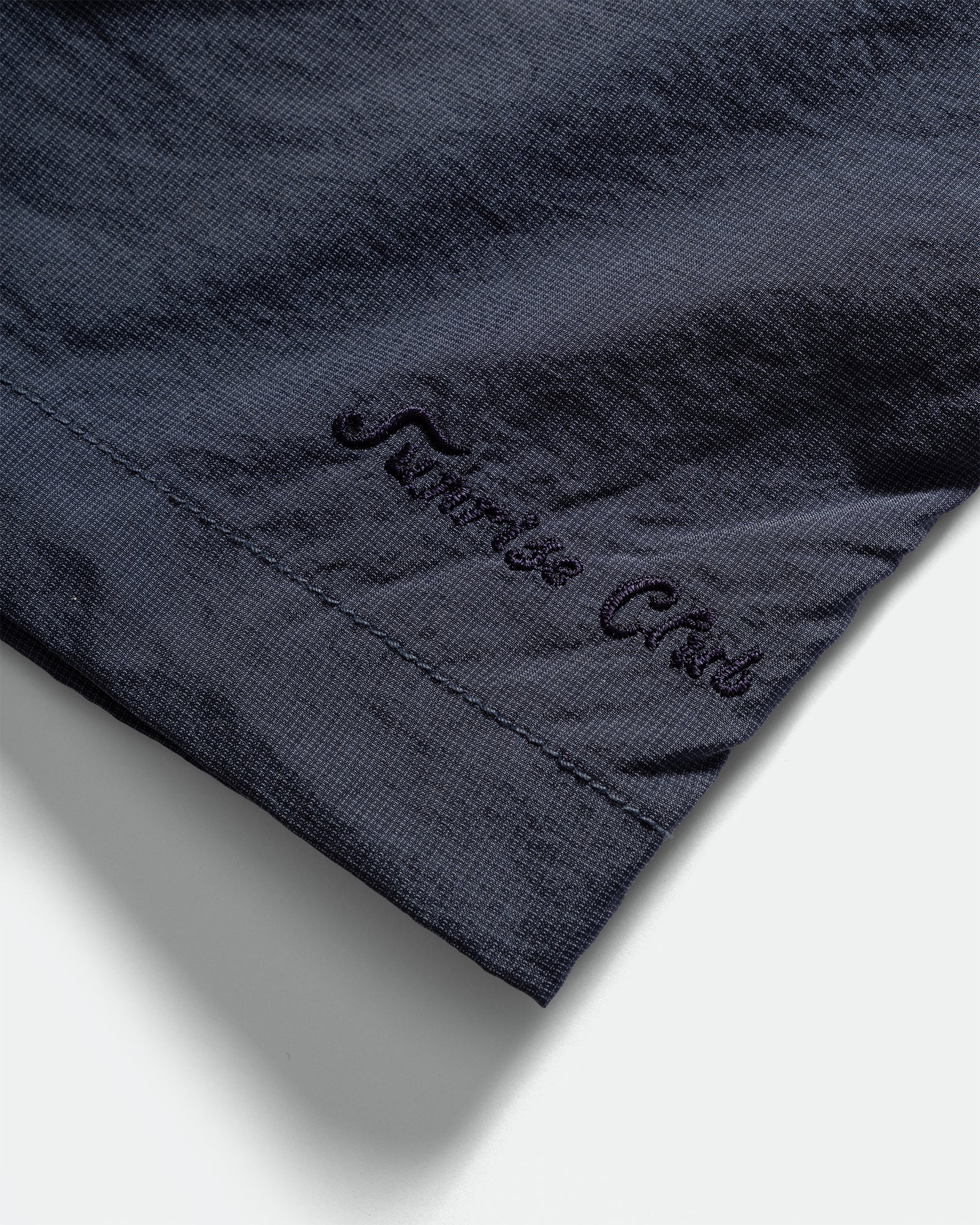 Close-up of a Kappy navy nylon shorts with 'Sunshine Club' embroidery on a grey background