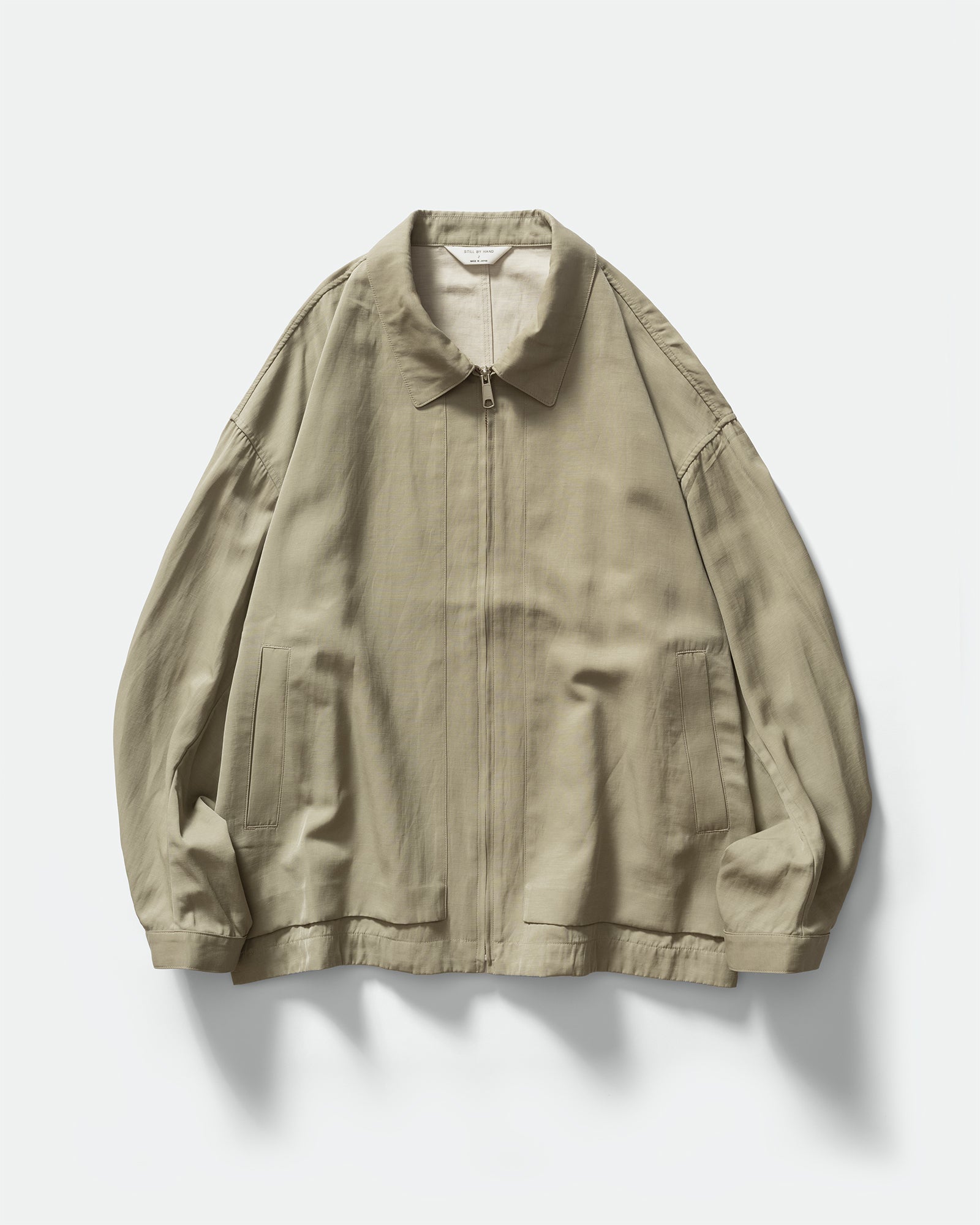 Pack shot of Still By Hand Sage Pigment Print Zip Blouson with collar, zip closure, slip pockets on a grey background.