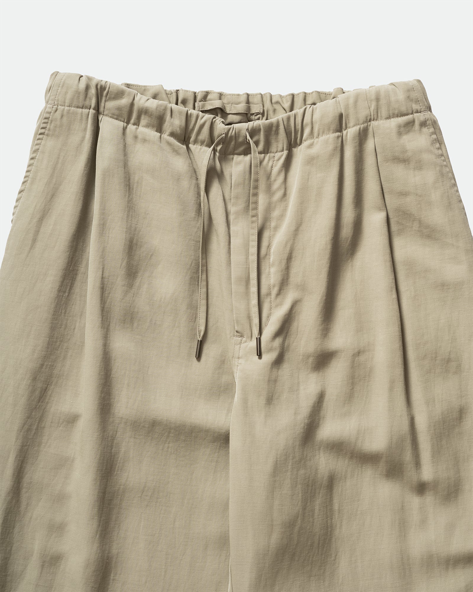 Close up of Still By Hand Sage Pigment Print Easy Pants with a drawstring waistband and slip pockets on a grey background.