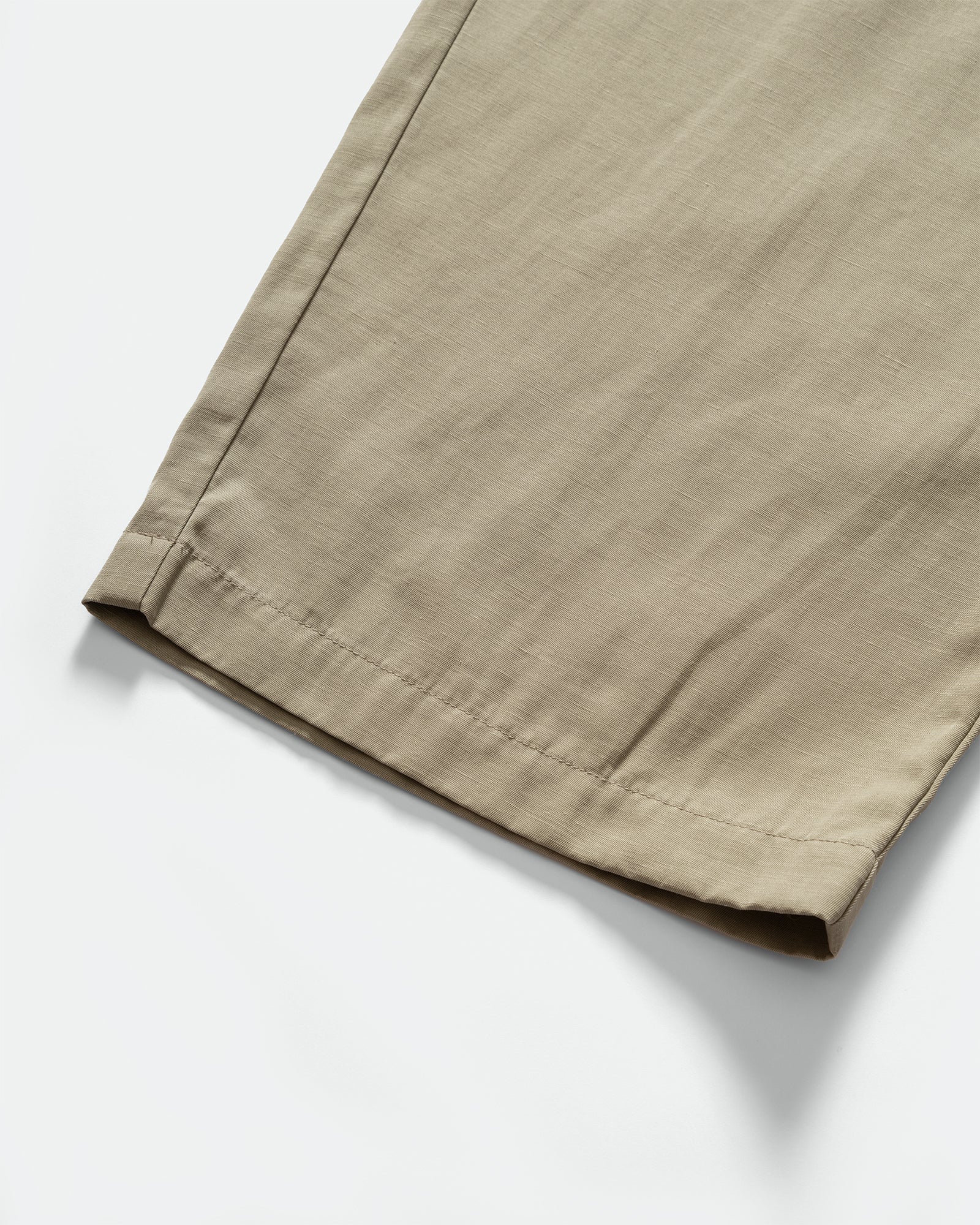 Side pack shot of Still By Hand Sage Pigment Print Easy Pants hem on a grey background.
