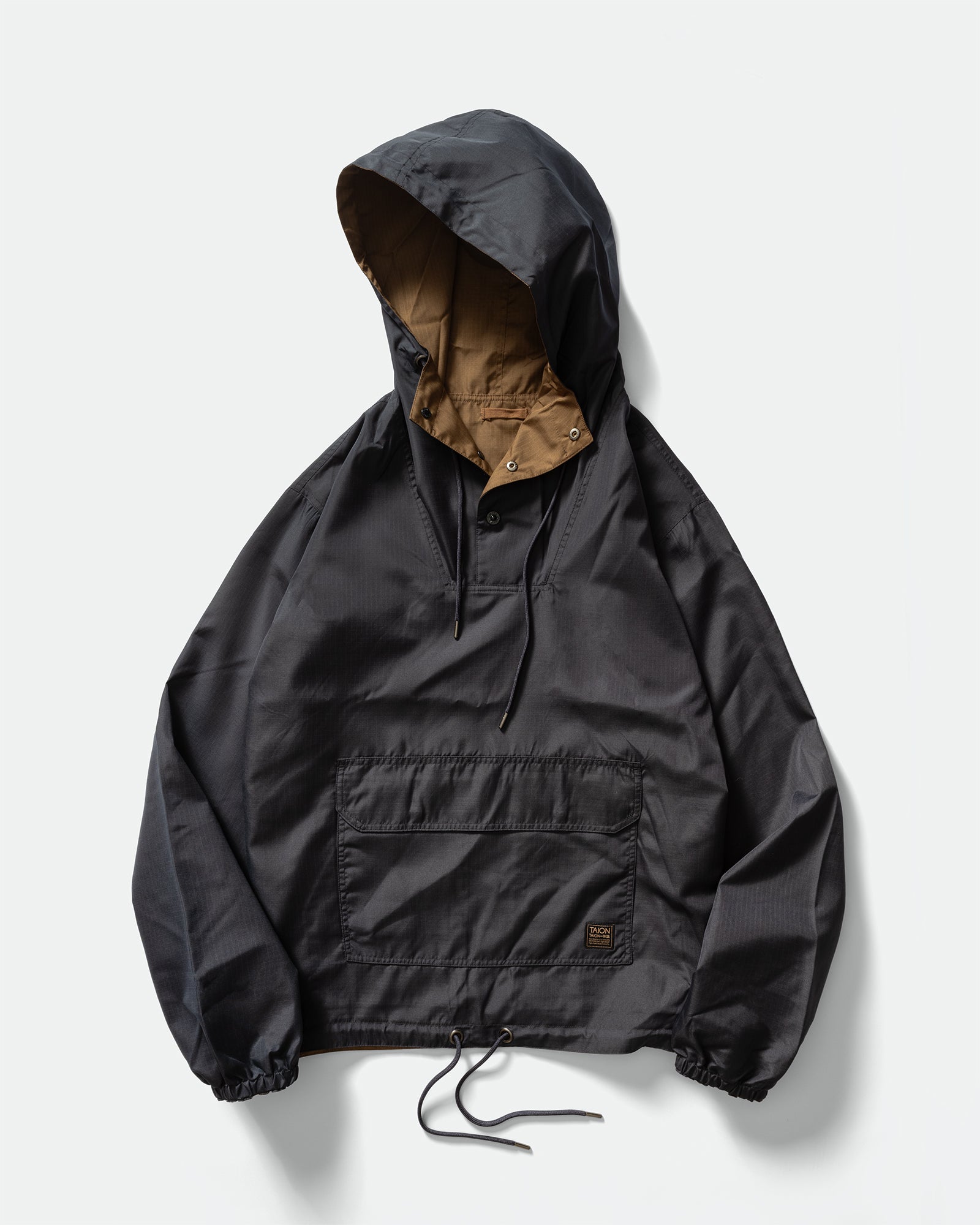 Pack shot of TAION Nylon Military Reversible Anorak Parka in Navy and Brown with snap button mock neck, drawstring hem, branded pocket on a grey background.