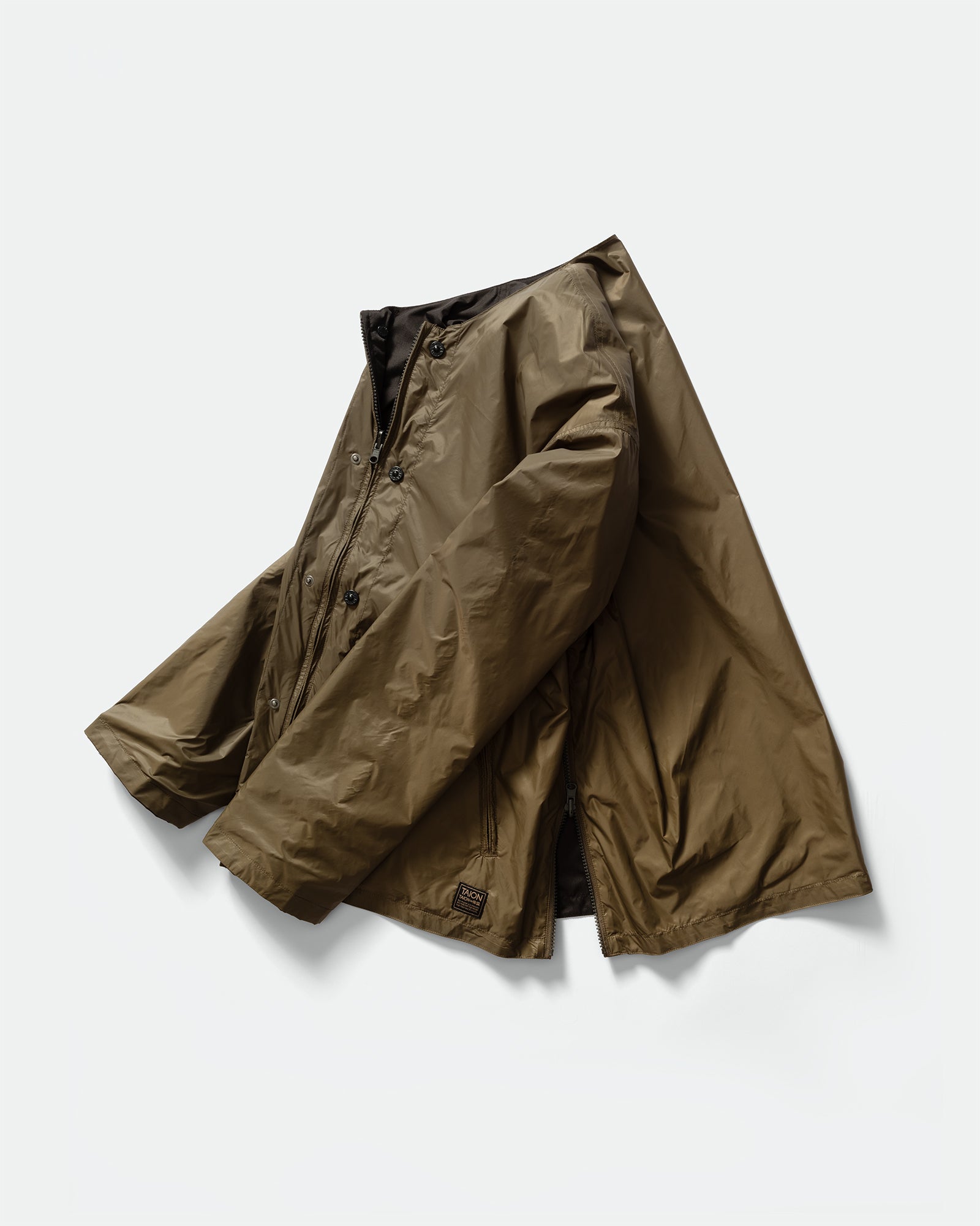 Side pack shot of TAION Nylon Military Reversible Liner Jacket in Dark Olive and Brown with zip closure, zip pockets, crewneck on a grey background.