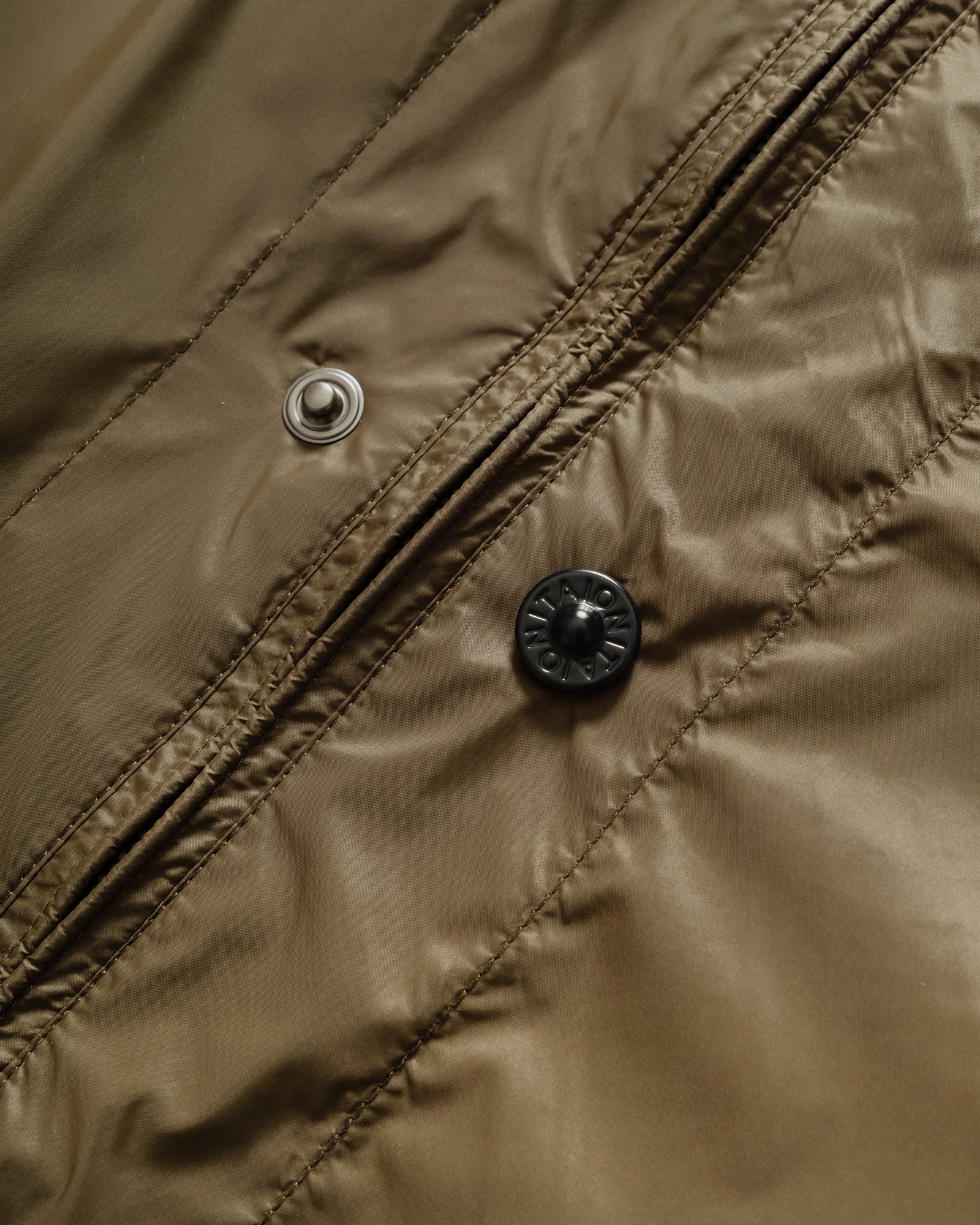 Close-up of TAION Nylon Military Reversible Liner Jacket in Dark Olive and Brown with zip closure and metal branded buttons.